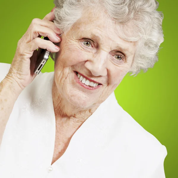 Portrét starší ženy mluví zelené pozadí na mobil — Stock fotografie