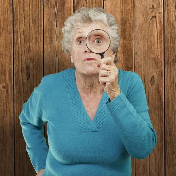 Portret van senior vrouw kijken door een vergrootglas agai — Stockfoto