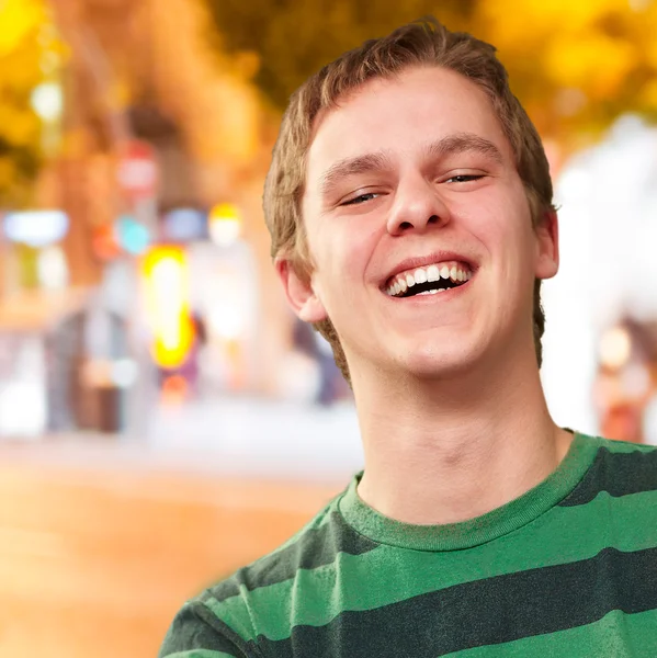 Portret van een jonge man die lacht tegen een nacht stad — Stockfoto