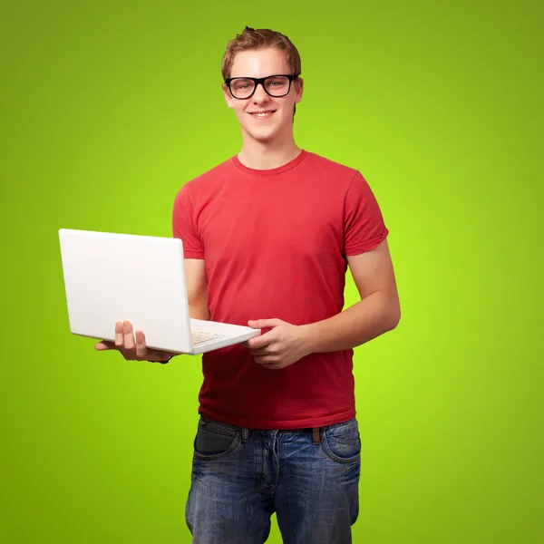 Retrato de jovem estudante segurando laptop sobre backgrou verde — Fotografia de Stock