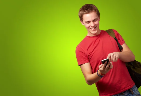 Porträt eines jungen Mannes, der Handybildschirm über grünem Hintergrund berührt — Stockfoto