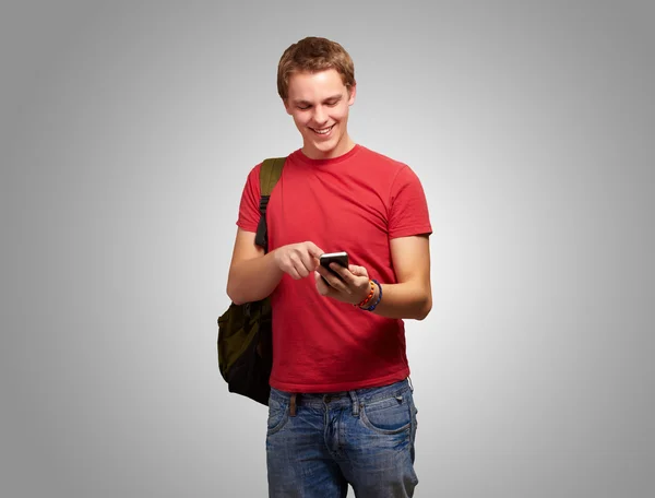 Portrét mladého muže dotknete mobilní obrazovky nad šedou poza — Stock fotografie