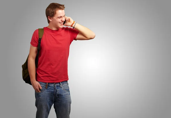 灰色の背景の上の携帯電話で話している若い男の肖像 — ストック写真