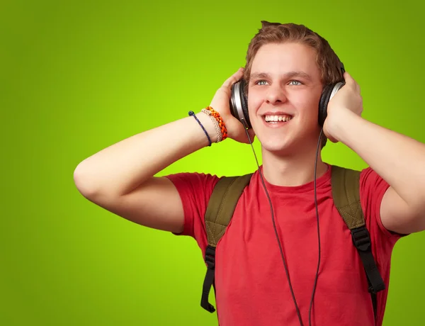 Портрет жизнерадостного молодого студента, слушающего музыку с хэдфоном — стоковое фото