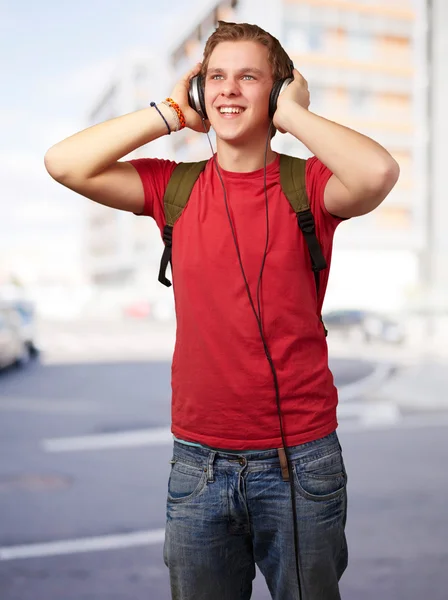 Ritratto di allegro giovane studente che ascolta musica con headphon — Foto Stock