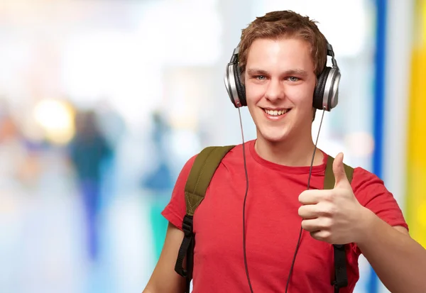 Portrait of cheerful young student listening music and gesturing
