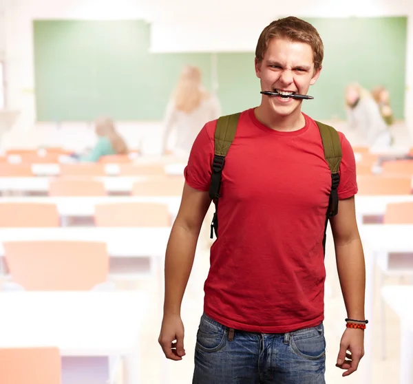 Retrato de jovem irritado mordendo caneta na sala de aula — Fotografia de Stock