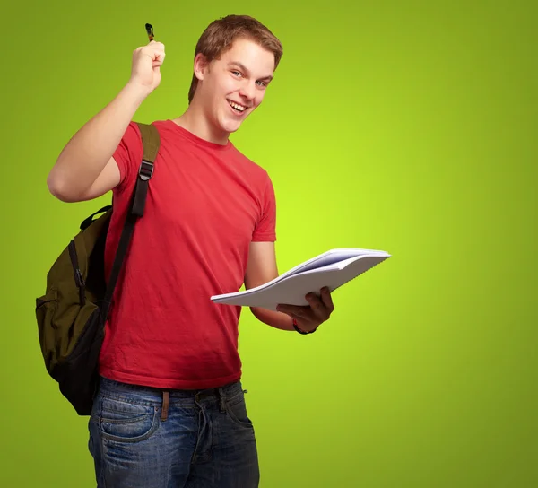 Portrét hezký studenta drží nad zelený notýsek a tužku — Stock fotografie