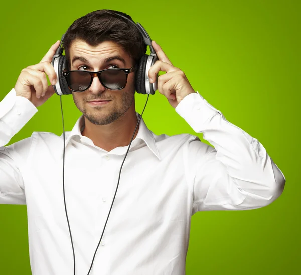 Porträtt av ung man lyssnar på musik med hörlurar via g — Stockfoto