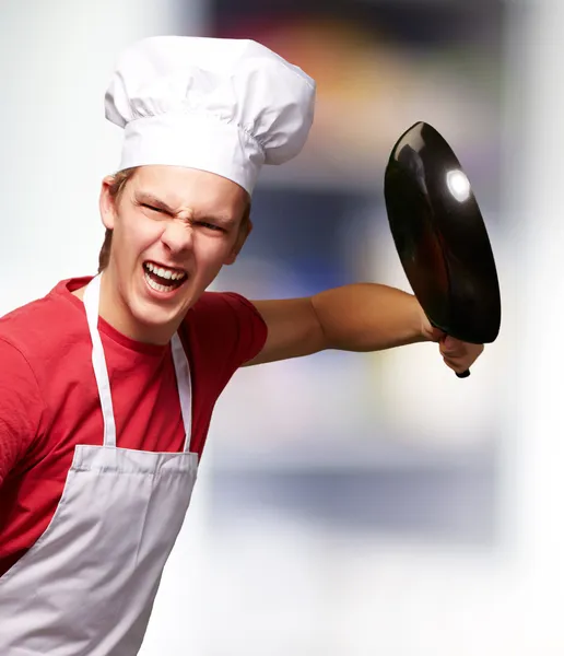 Pan ile kapalı isabet kızgın genç aşçı adam portresi — Stok fotoğraf