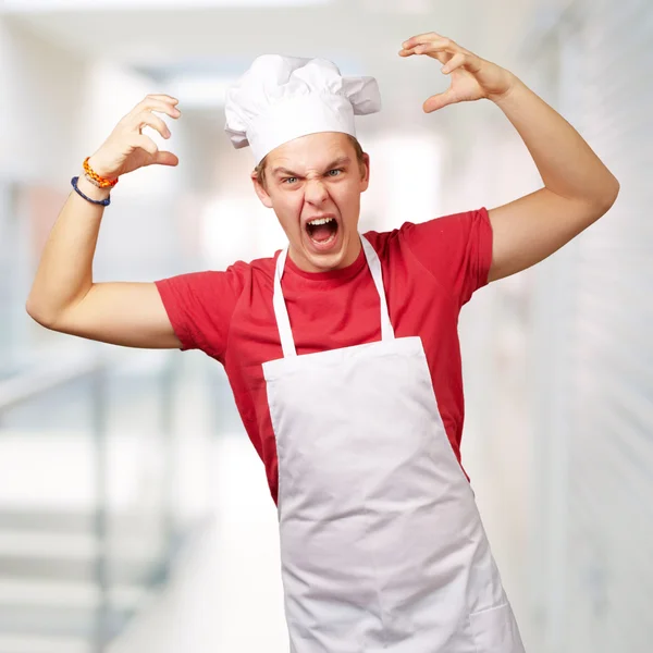 Portrait of young cook man wearing apron doing aggressive gestur — Stock Photo, Image