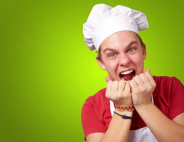 Portret van jonge kok man schreeuwen op groene achtergrond — Stockfoto