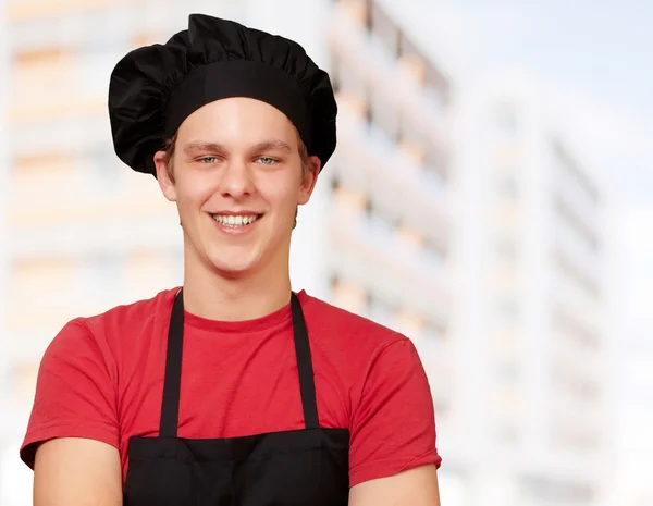 Portret van jonge kok man dragen uniform en glimlachend tegen een — Stockfoto
