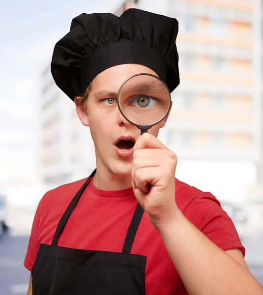 Portrait de jeune cuisinier regardant à travers une loupe ag — Photo