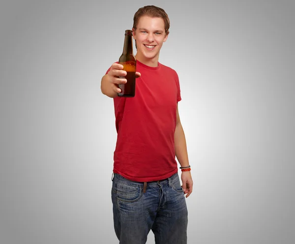 Retrato de jovem segurando cerveja sobre fundo cinza — Fotografia de Stock
