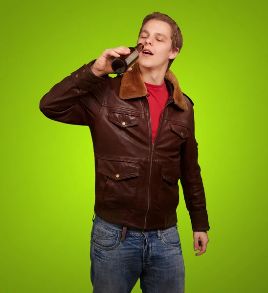 年轻人喝啤酒在绿色背景下的肖像 — 图库照片