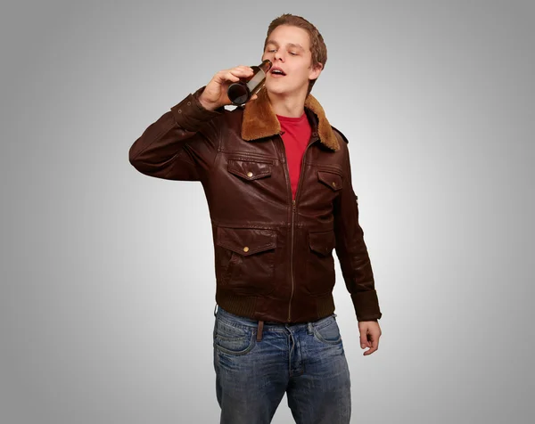 Portret młodzieńca picia piwa na szarym tle — Zdjęcie stockowe