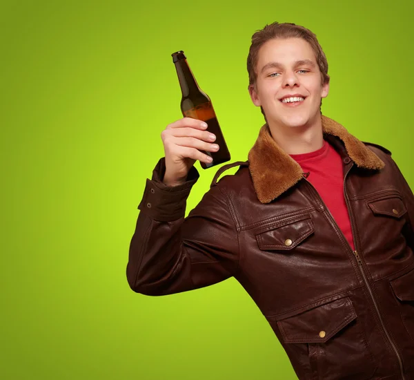 Portret van jonge man houden van bier op groene achtergrond — Stockfoto