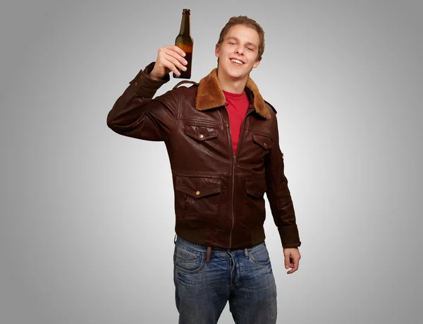 Portret młodzieńca gospodarstwa piwa na szarym tle — Zdjęcie stockowe