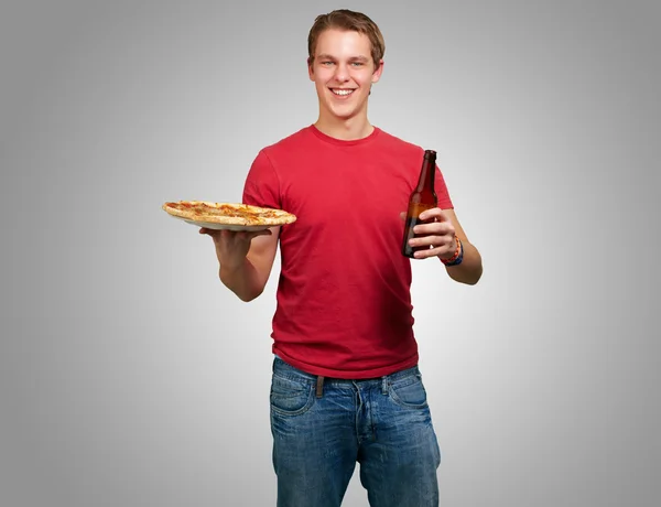 Podobizna mladého muže drží pizzu a pivo nad šedou poza — Stock fotografie