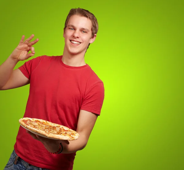 Pizza holding ve iyi bir jest yapıyor genç adam portresi — Stok fotoğraf