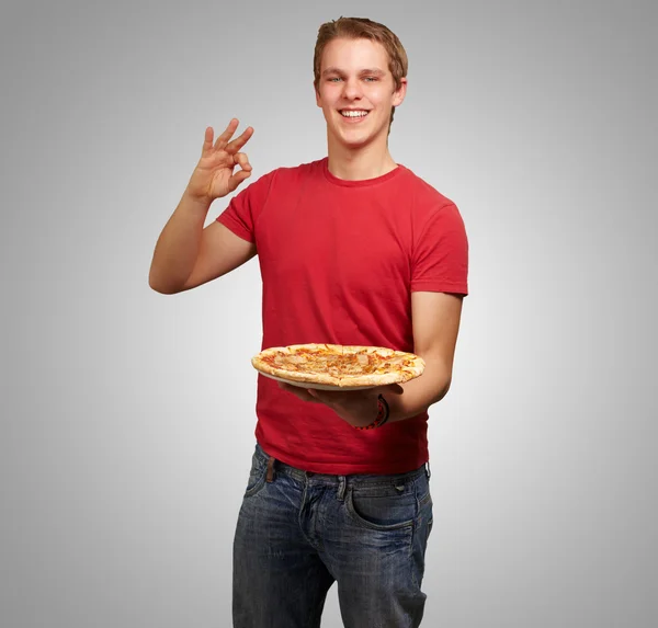 Retrato do jovem segurando pizza e fazendo um bom gesto — Fotografia de Stock