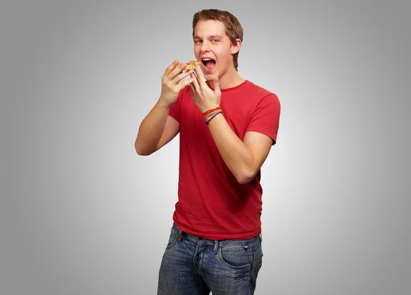 Portré, fiatal ember eszik pizza felett szürke háttér — Stock Fotó