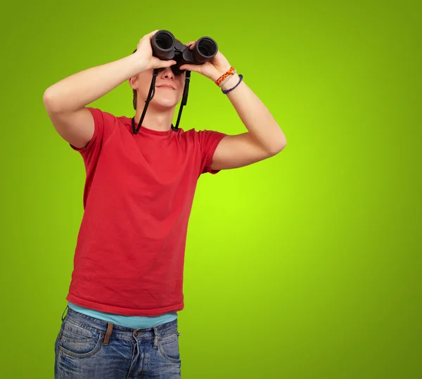 緑の背景の上の双眼鏡を持つ若者の肖像 — ストック写真