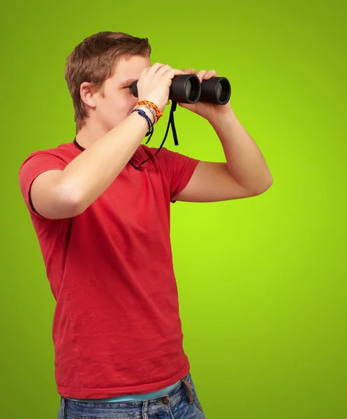 透过双筒望远镜望绿坝的年轻男子的画像 — 图库照片