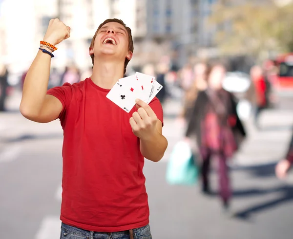 Portrait of young man doing a winner gesture playing poker at cr — Stock Photo, Image