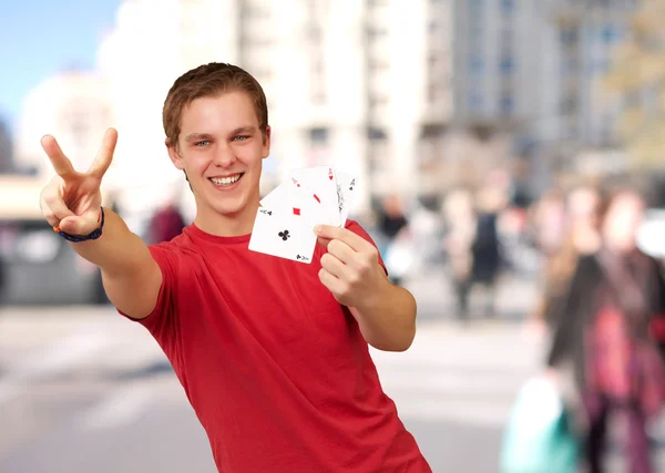 Porträt eines jungen Mannes, der eine Siegesgeste macht und bei c Poker spielt — Stockfoto