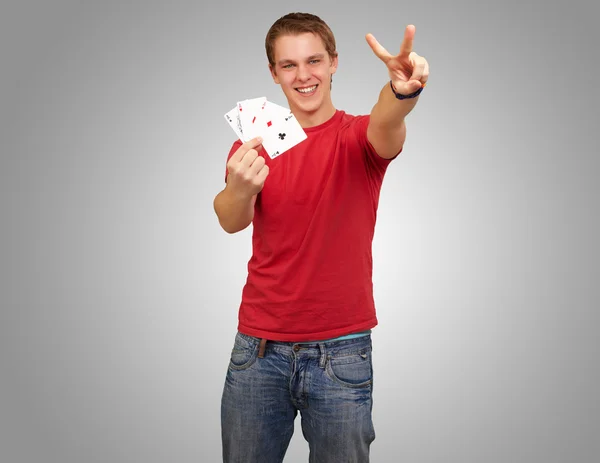 Retrato de um jovem fazendo um gesto de vitória jogando poker sobre — Fotografia de Stock