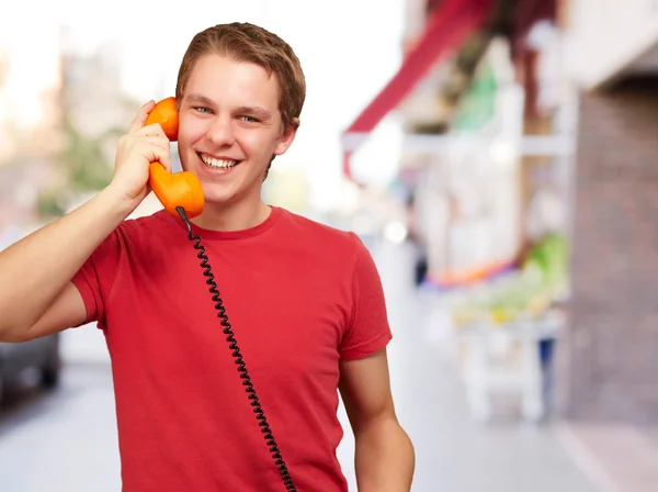 Портрет молодого человека, разговаривающего с винтажным телефоном на улице — стоковое фото