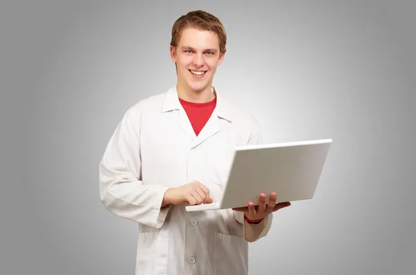 Ritratto di giovane studente che tiene il computer portatile su sfondo grigio — Foto Stock