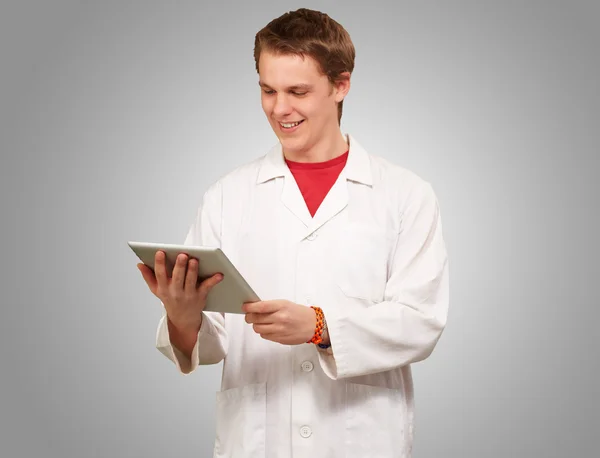 Portrait of young academic holding a digital tablet over grey ba — Stock Photo, Image