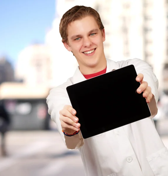 Porträtt av ung man visar digitala tablett mot en byggnad — Stockfoto