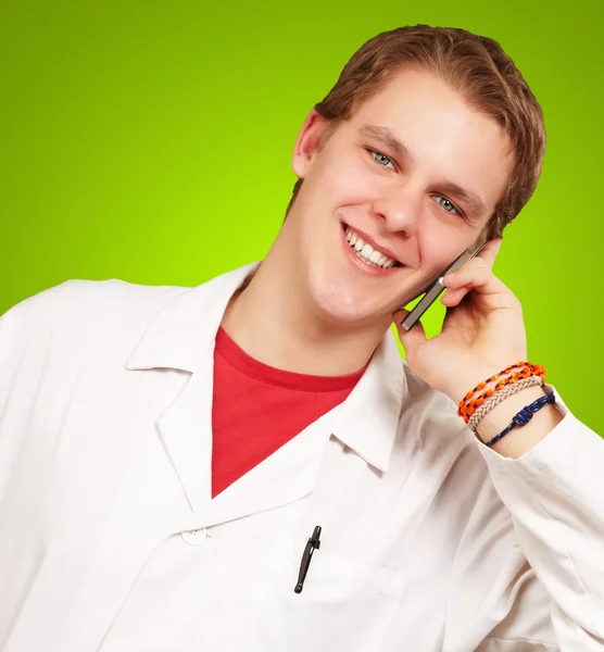 Portrait of young academic talking on mobile over green backgrou — Stock Photo, Image