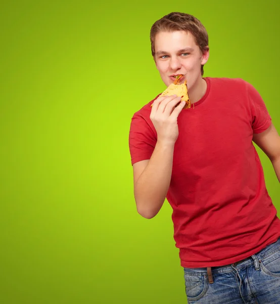 Portrét mladého muže jíst pizzu nad zeleným pozadím — Stock fotografie
