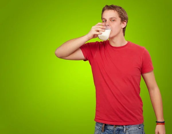 Портрет молодого человека, пьющего молоко на зеленом фоне — стоковое фото