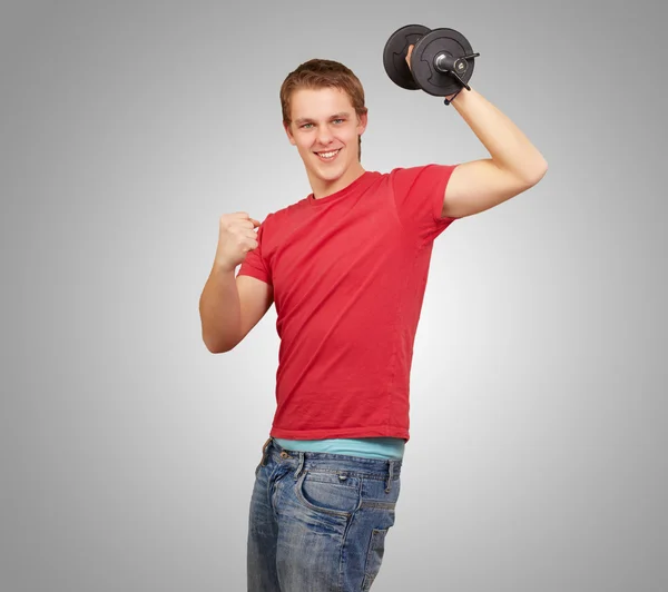 Joven haciendo fitness con pesas sobre fondo gris — Foto de Stock