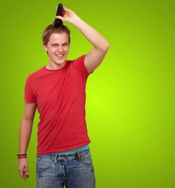 Retrato del joven cortándose el pelo sobre fondo verde — Foto de Stock