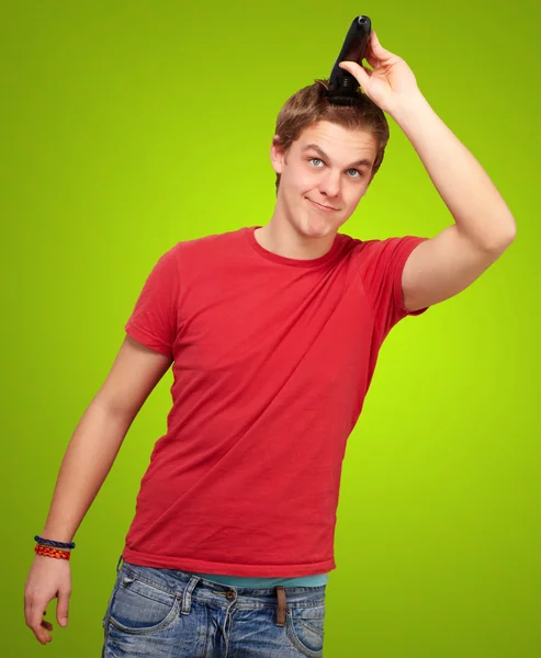 Portret van een jonge man die zijn haar knippen op groene achtergrond — Stockfoto