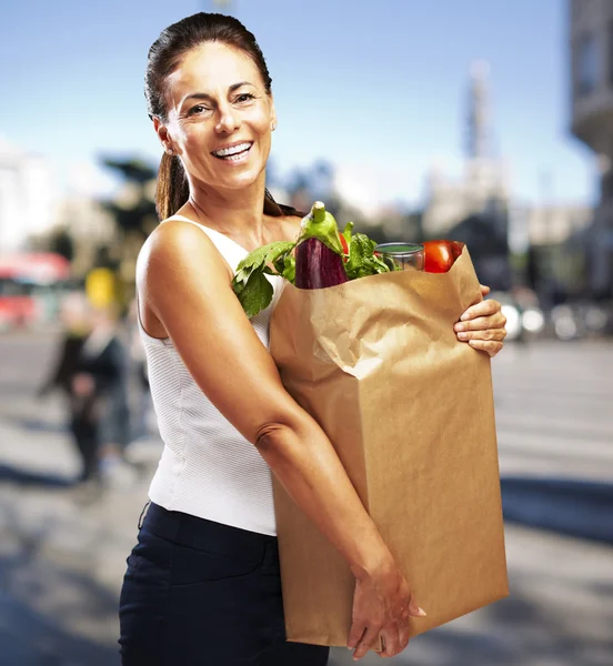 Retrato de mulher de meia-idade carregando compra em um str lotado — Fotografia de Stock
