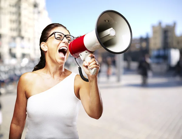 Portrait of a middle aged woman shouting with megaphone at a cro — Stock Photo, Image