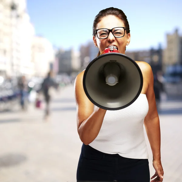 Portrait of a middle aged woman shouting with megaphone at a cro — Stock Photo, Image