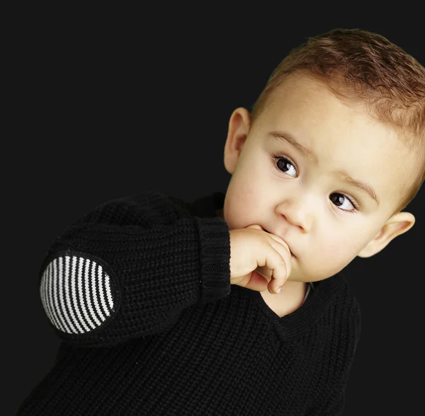 Retrato de niño adorable pensando sobre un fondo negro — Foto de Stock