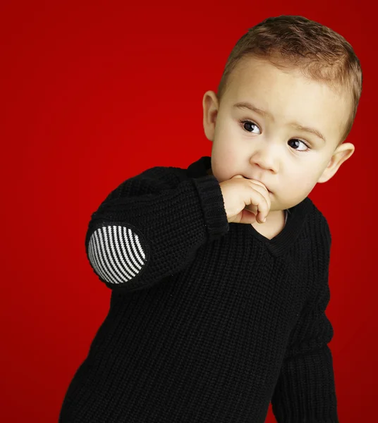Retrato de niño adorable pensando sobre un fondo rojo — Foto de Stock