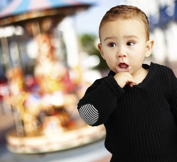 Portrait of a adorable thoughful kid near a carousel — Stock Photo, Image