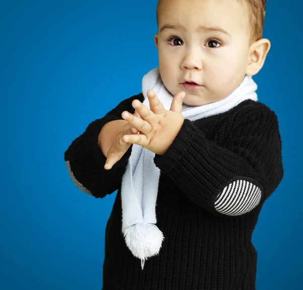 Retrato de niño adorable aplaudiendo contra un fondo azul — Foto de Stock