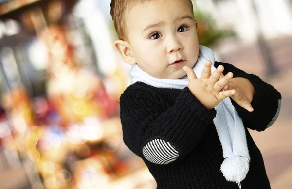 Retrato de niño adorable aplaudiendo contra un carrusel — Foto de Stock